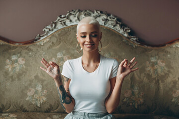 Millenial young woman with short blonde hair portrait sitting and meditate with ok sign mudra on...