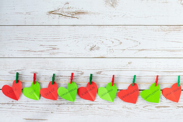 Paper hearts in red and green color with colorful clothespin hanging on a rustic line with biblical...