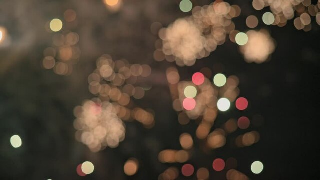 Blurred bokeh. Bright colorful festive glowing fireworks on dark night sky. New Year, Christmas, festival, party, holiday celebration. Fireworks background, real footage 4K