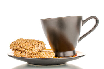 Several sweet roasted sweets from sunflower seeds and honey on a black saucer with a cup, macro, isolated on a white background.