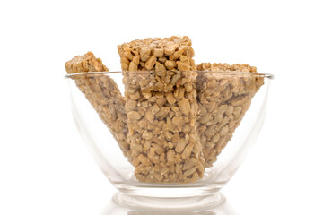 Several sweet roasted candies from sunflower seeds and honey in a glass bowl, macro, isolated on a white background.