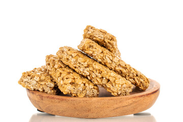 Several sweet roasted sweets from sunflower seeds and honey on a wooden saucer, macro, isolated on a white background.