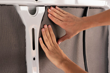 Close up view of unrecognizable young man hands placing and installing the isolation of a camper...