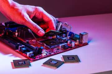 A man's hand inserts a processor into the motherboard chipset