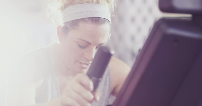 Real, tired and sporty woman sweating at the gym while cycling on an exercise bike. A normal person doing a cardio workout to build stamina and endurance during fitness training at a health club