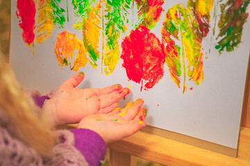 little girl artist with paints in her hands in autumn in the park draws a landscape with leaves on...