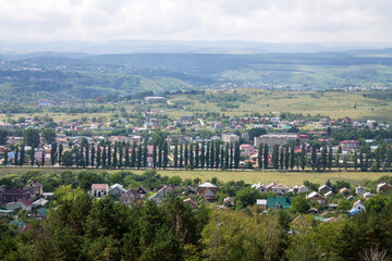 Panoramic top view of the city of Kislovodsk in Russia with green trees and architecture through a misty haze on a sunny summer day and a sky with clouds and copy space