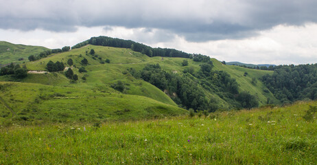 Naklejka premium landscape - panoramic view of the hills and green valley from the Maloe Sedlo mountain in Kislovodsk Russia on a cloudy summer day