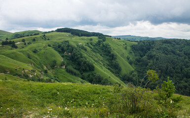 Naklejka na ściany i meble landscape - panoramic view of the hills and green valley from the Maloe Sedlo mountain in Kislovodsk Russia on a cloudy summer day