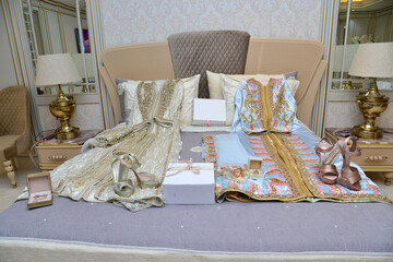 Moroccan caftan with the bride's shoes on the bed waiting for the bride to wear the wedding clothes