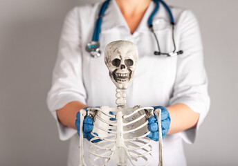 Doctor showing human skeleton. Woman in lab coat with stethoscope teaching anatomy to students....