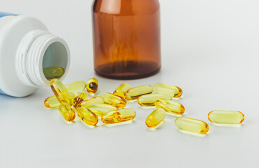 Close up (zoom) of fish oils capsules dietary supplement for health care. Isolated on white background with brown pill bottle.