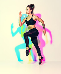 Fototapeta na wymiar Sporty woman runner in silhouette. Photo of muscular woman in black sportswear on white background with effect of rgb colors shadows. Dynamic movement. Side view. Sport and healthy lifestyle