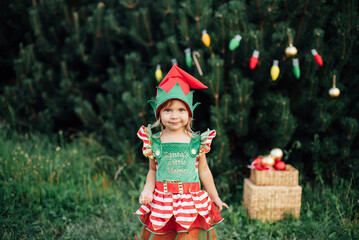Fototapeta Child waiting for Christmas in wood in juli. portrait of little girl near christmas tree. Baby decorating pine. winter holidays and people concept. Merry Christmas and Happy Holidays. obraz