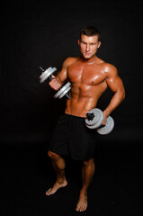 Fototapeta na wymiar Young attractive sportsman with dumbbells. Male athletic body. 