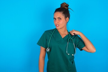 beautiful doctor woman wearing medical uniform over blue background stressed, anxious, tired and frustrated, pulling shirt neck, looking frustrated with problem