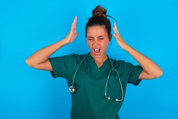 beautiful doctor woman wearing medical uniform over blue background goes crazy as head goes around...