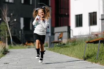 Obraz premium a little girl goes to school through the park along the path. distance education concept. schoolgirl returning home from school 