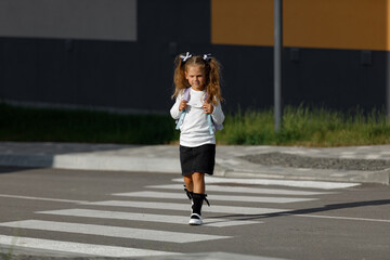 Fototapeta na wymiar schoolgirl crosses the road at a pedestrian crossing 