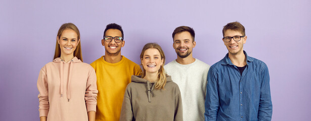 Portrait of group of young, smart and positive multiracial people on purple background....