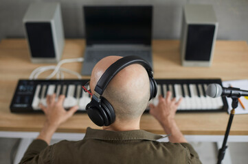 Close up top view of man musician in headphones play synthesizer compose music in studio. Male...