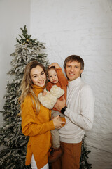 mom and dad with little son play against the background of the christmas tree