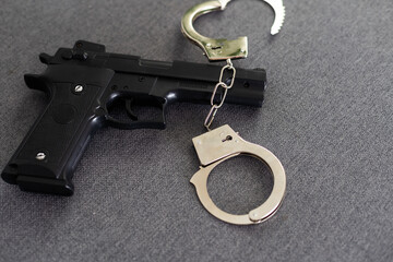 Black gun and metal handcuffs lie on the black background. Private detective work. Searching...