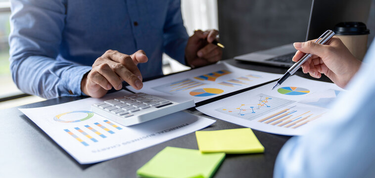 Business and partnership discussing using calculator to review balance sheet annual with holding pen and using laptop computer to calculating budget. audit integrity before investment concept.