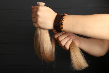 The male hand holds sections of hair for extension.