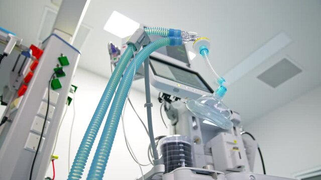 Modern surgery room with advanced equipment. Oxygen mask with blue tubes hanging near apparatus for lung ventilation. Low angle view.