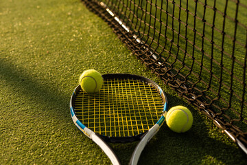 A tennis racket and new tennis ball on a freshly painted tennis court.