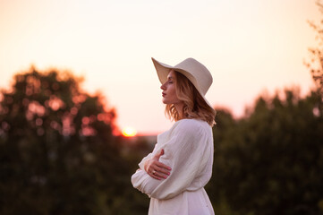 beautiful young woman in white dress and hat on the lavander field