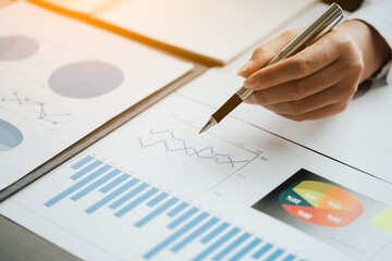 Close up of business hands working and calculating on financial and accounting graft and chart in office space. And ray light.