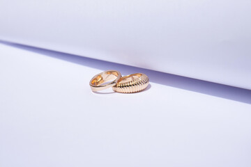 Two gold wedding rings on white background with contrasting shadows