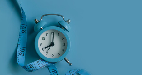 Alarm clock, measuring tape on a colored background