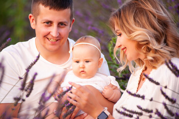 Beautiful portrait of a young family with baby in lavender field. Family love and value concept.