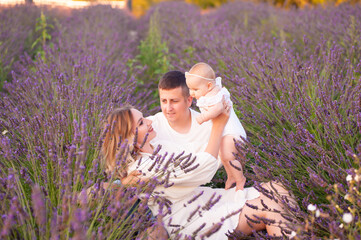 Beautiful portrait of a young family with baby in lavender field. Family love and value concept.