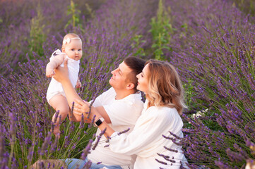 Beautiful portrait of a young family with baby in lavender field. Family love and value concept.