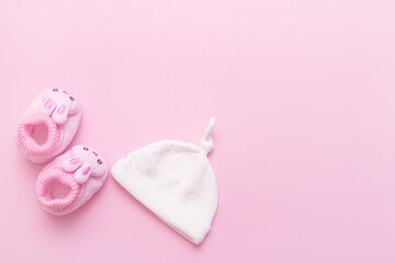 booties in the form of hares and a cap for a baby on a pink background with copy space
