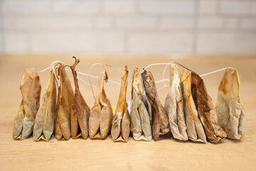 Used tea bags are stored in a row on a white and wooden background. Tea bags for reuse. Recycling...