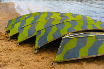 wooden boats overturned on the shore of the lake