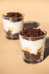 Maulwurfskuchen im Glas mit Stracciatella und Banane auf einem orangen Untergrund