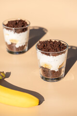 Maulwurfskuchen im Glas mit Stracciatella und Banane auf einem orangen Untergrund