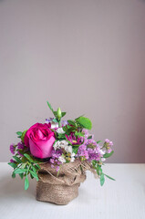 Beautiful summer bouquet of flowers on the white wooden table with pink background.