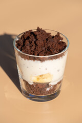 Maulwurfskuchen im Glas mit Stracciatella und Banane auf einem orangen Untergrund