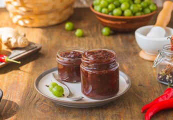 Sauce, gooseberry chutney in a glass jar on a wooden background in rustic style. Indian food. Recipes for sauces