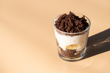 Maulwurfskuchen im Glas mit Stracciatella und Banane auf einem orangen Untergrund
