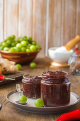 Sauce, gooseberry chutney in a glass jar on a wooden background in rustic style. Indian food. Recipes for sauces