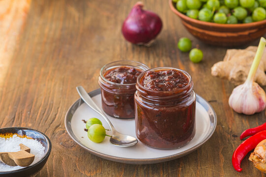 Sauce, gooseberry chutney in a glass jar on a wooden background in rustic style. Indian food. Recipes for sauces