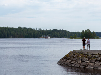 Elderly caucasian couple taking pictures of a big ship on the lake.